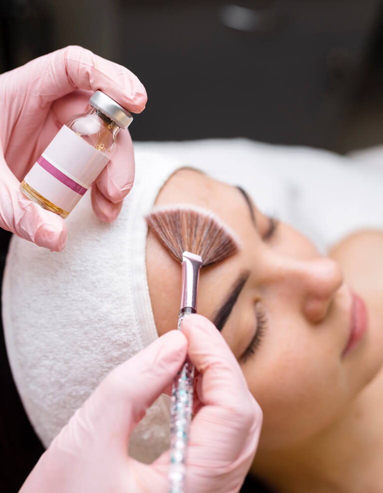 A woman relaxes while having a chemical peel applied to her face.