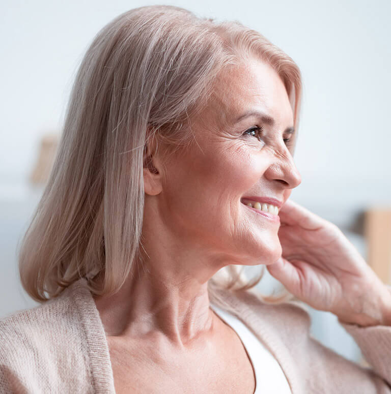Close up profile of a smiling mature woman, looking ahead.