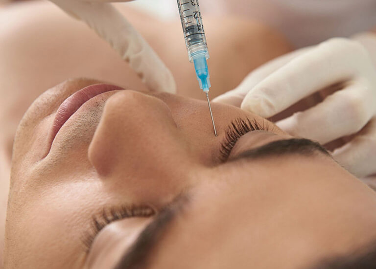 Close up of a person receiving a dermal injection under her eye.