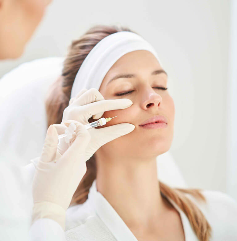 A woman receives a botox injection from an unseen beauty professional.
